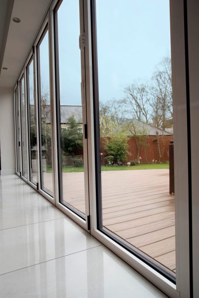 Closed white aluminium bifolding doors leading to a wooden patio