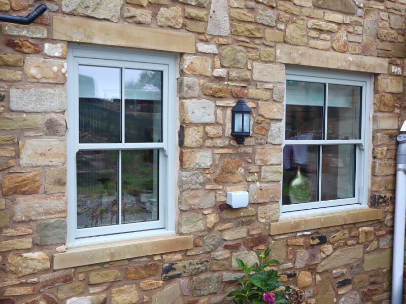 Heritage-style uPVC sliding sash windows fitted to a traditional stone cottage