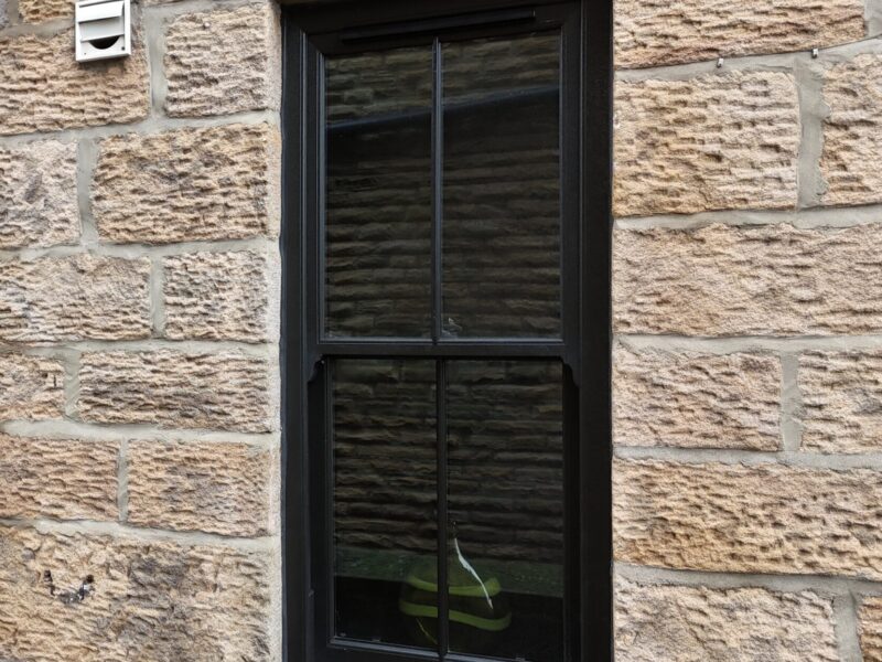 Black woodgrain vertical slider windows enhancing a period home exterior