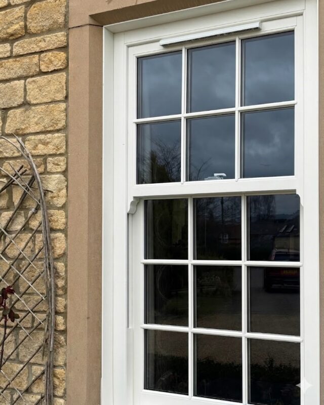 Chalk White uPVC sliding sash window installed on a traditional stone property with glazing bars