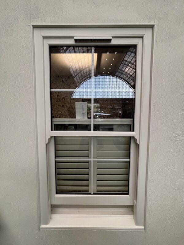 Traditional style uPVC sliding sash window with white woodgrain finish and slim midrail replicating timber proportions