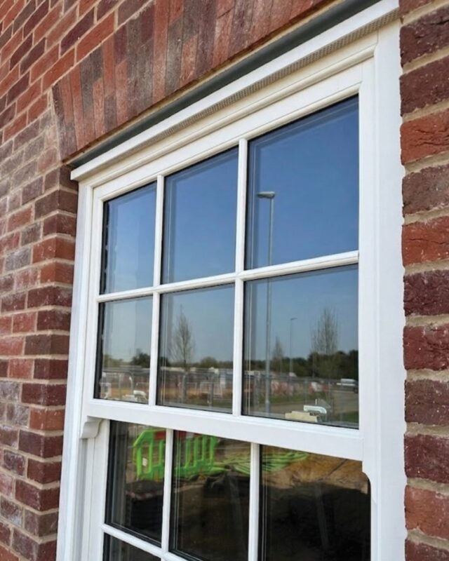 White heritage-style uPVC sash window with concealed head vent above the frame
